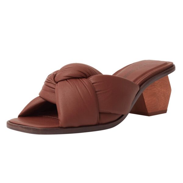 Mule de luxo em couro caramelo, com cabedal de nó robusto e salto geométrico esculpido em madeira maciça.